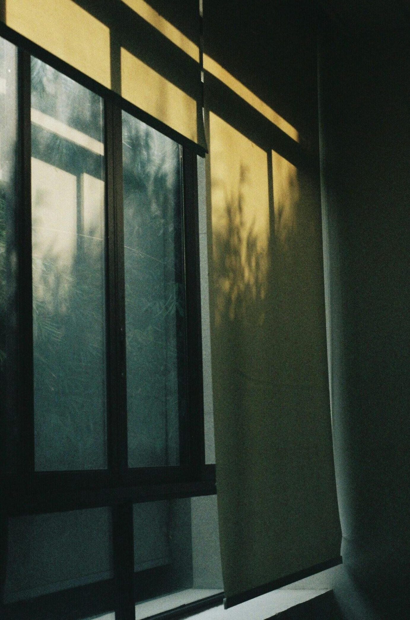 Warm sunlight filters through roller blinds, casting shadows indoors.